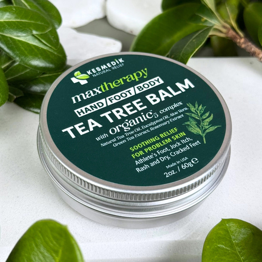 Kesmedik Tea Tree Balm surrounded by botanical leaves.